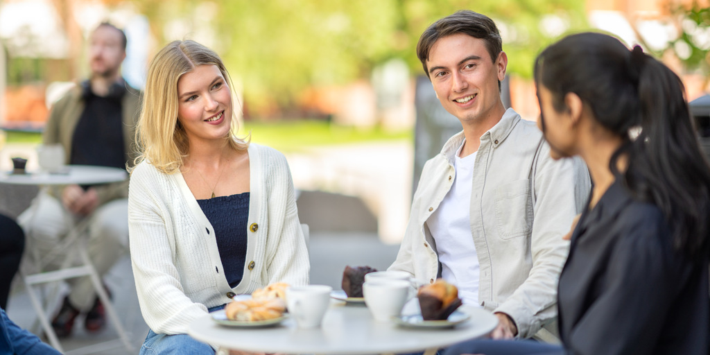 Tre studenter diskuterar fikas på KTH Campus