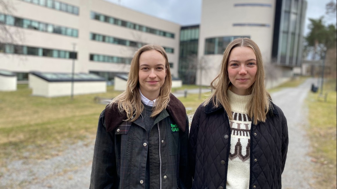 Two women in front of white buildings.