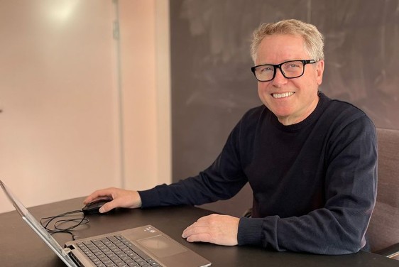 A man in glasses sitting in front of a laptop computer