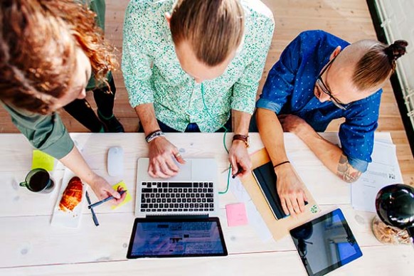 Three people sitting at a table with a laptop.