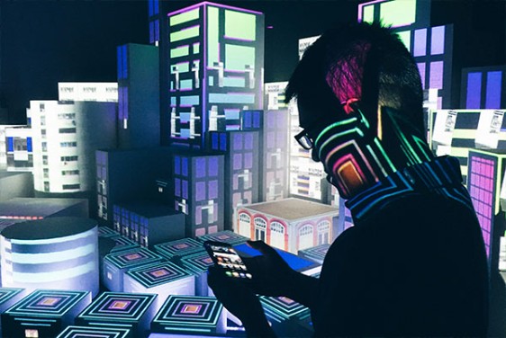 En person håller en telefon och står framför en bild som visar en futuristisk 3D-stad