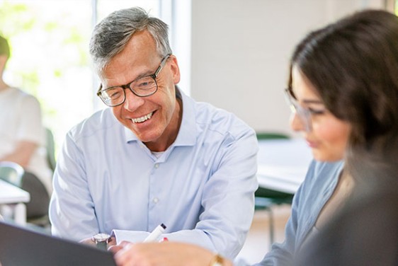 A teacher and a student are sitting by a laptop.