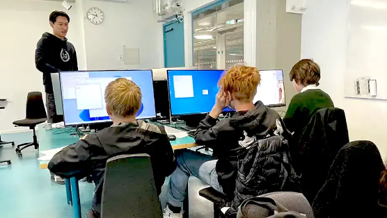 a person in a KTH hoodie and a group of pupils sitting in front of screens