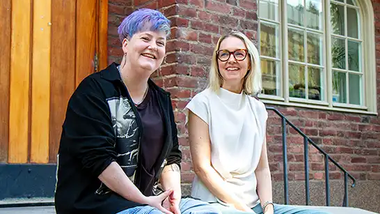 Two persons sitting and looking into the camera.