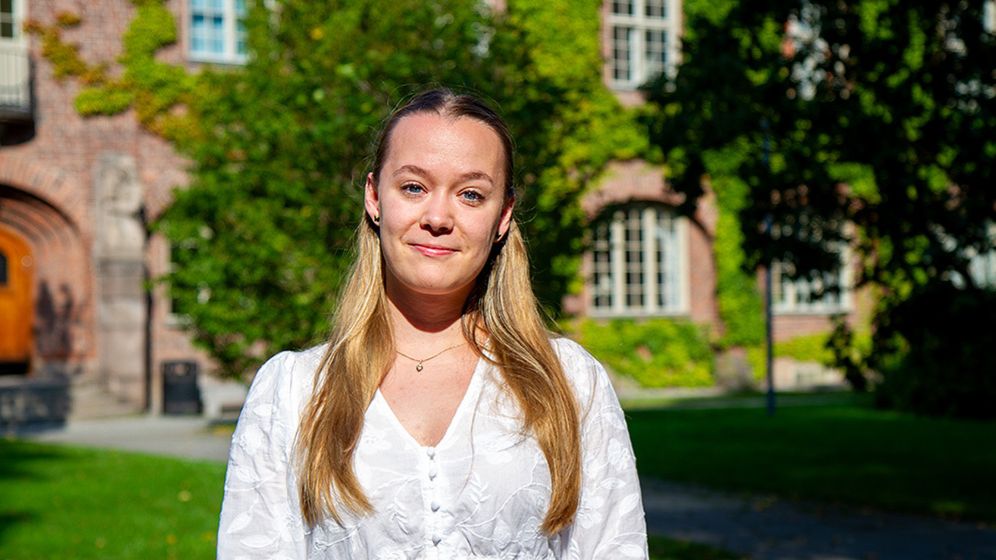 Woman in front of a courtyard with brick buildings.
